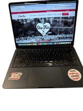 Load image into Gallery viewer, Laptop on a white surface with a website displayed on the screen and stickers on the keyboard.
